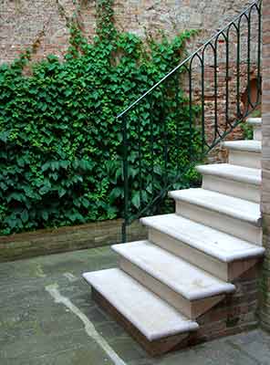 Montée d'escalier extérieure en pierre sur muret en briques....